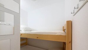Ein Stockbett mit Holzrahmen und weißer Bettwäsche.