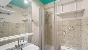Ein Badezimmer mit Waschbecken, Spiegel, Dusche und Toilette.