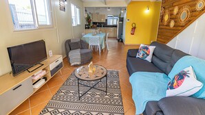 A living room with a sofa, TV, and a patterned rug. - Quiet 3-suite house with 4 bedrooms - Assured water - Between sea and mountains. (Baie-Mahault)