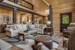 A spacious living room with a high ceiling, wooden walls, and a large window. - Catawba Falls Retreat, Views, Hot Tub & Game Room (Black Mountain)