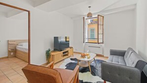 Een moderne, goed verlichte kamer met een bed, een televisie, een bank en een eethoek.