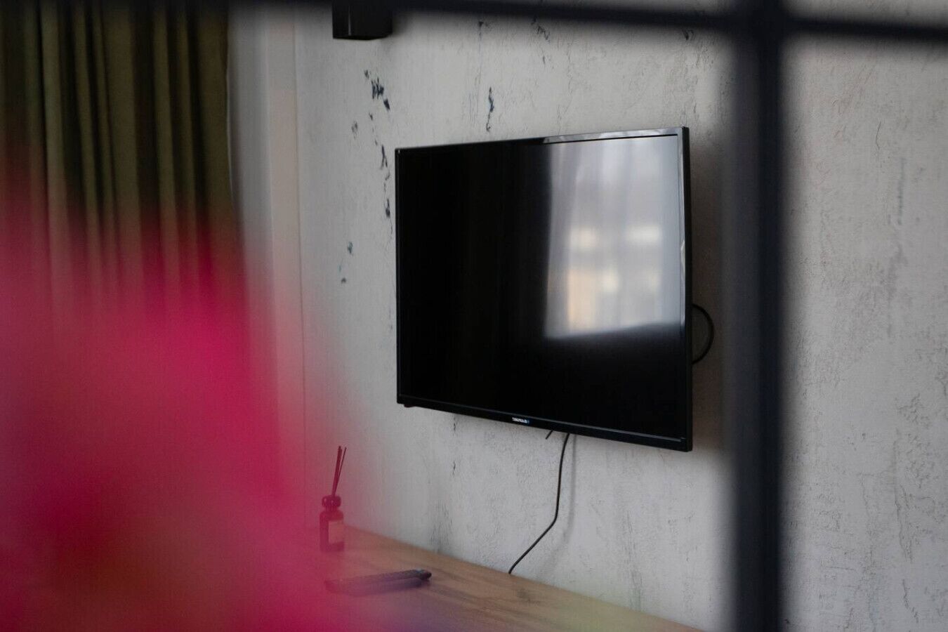 Een flatscreen televisie bevestigd aan een effen muur, met een houten tafel ervoor.