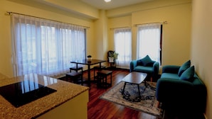 A spacious living room with a dining area, two sofas, a coffee table, and a kitchen area with a granite countertop and a built-in stove. - Eutsholing Boutique Hotel (Thimphu)