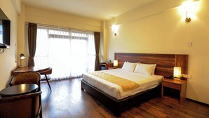 A hotel room with a large bed, a desk with a chair, a flat-screen TV, and a window with curtains. - Eutsholing Boutique Hotel (Thimphu)