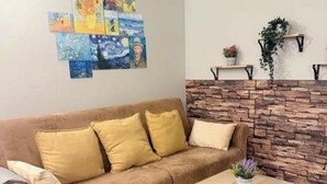 Una sala de estar con un sofá marrón, una mesa de centro de madera y una pared de piedra.