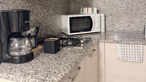 Una cocina con encimera de granito, cafetera, microondas y estufa a gas.