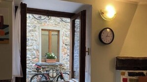 Una habitación con ventana que da a un muro de piedra, un radiador, un reloj y una chimenea.