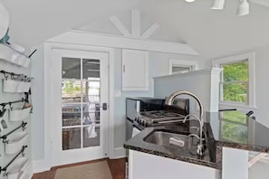 A kitchen with a gas stove, stainless steel sink, and white cabinetry.