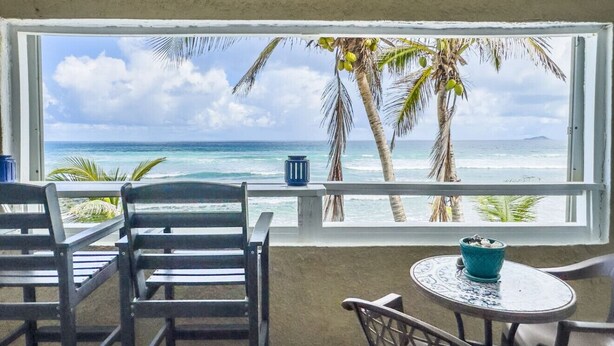 Ein Zimmer mit Meerblick, ein Fenster, ein Tisch mit Stühlen und eine dekorative Schale.