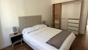 Ein Schlafzimmer mit Bett, Nachttischen, einem Kleiderschrank und einer Pendelleuchte.