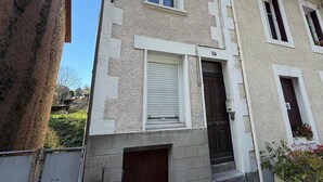 Ein zweistöckiges Gebäude mit einer Stein-Fassade, einer dunkelbraunen Tür und einem kleinen Fenster im Obergeschoss.