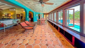 A spacious indoor area with a tiled floor, a ceiling fan, and a pool visible through large windows. - Panorama Pool House - 3 BR/3BA! (Christiansted)