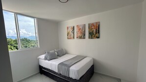 Ein Schlafzimmer mit einem Bett, einem Fenster und drei an der Wand befestigten Kunstwerken.