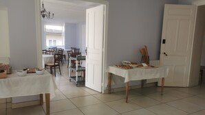 A dining area with tables, chairs, a chandelier, and a door.