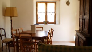 Un coin repas comprenant une table, des chaises, une lampe et une fenêtre avec des rideaux.