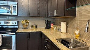 A modern kitchen with dark wood cabinets, stainless steel appliances, and a granite countertop.
