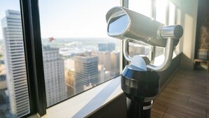 A telescope on a windowsill overlooking a cityscape.