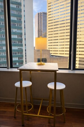 A small table with a lamp and two stools in a room with large windows overlooking a cityscape. - Luxury Downtown Dallas Condo Skyline Views + Parking (Dallas)