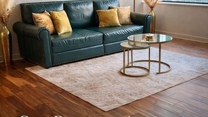 A cozy downtown apartment with a green leather sofa, a round glass coffee table, and a large abstract painting on the wall.