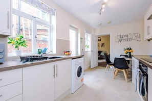 A modern kitchen with a built-in washing machine, a dining area with a table and chairs, and a wall with French phrases.