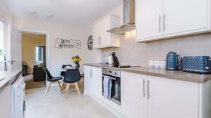 A modern kitchen with white cabinets, a built-in oven, and a coffee maker.