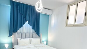 A bedroom with a bed, a nightstand, a wall-mounted air conditioner, and a window with blinds. - Tiffany`s Apartment Sea View (Durrës)
