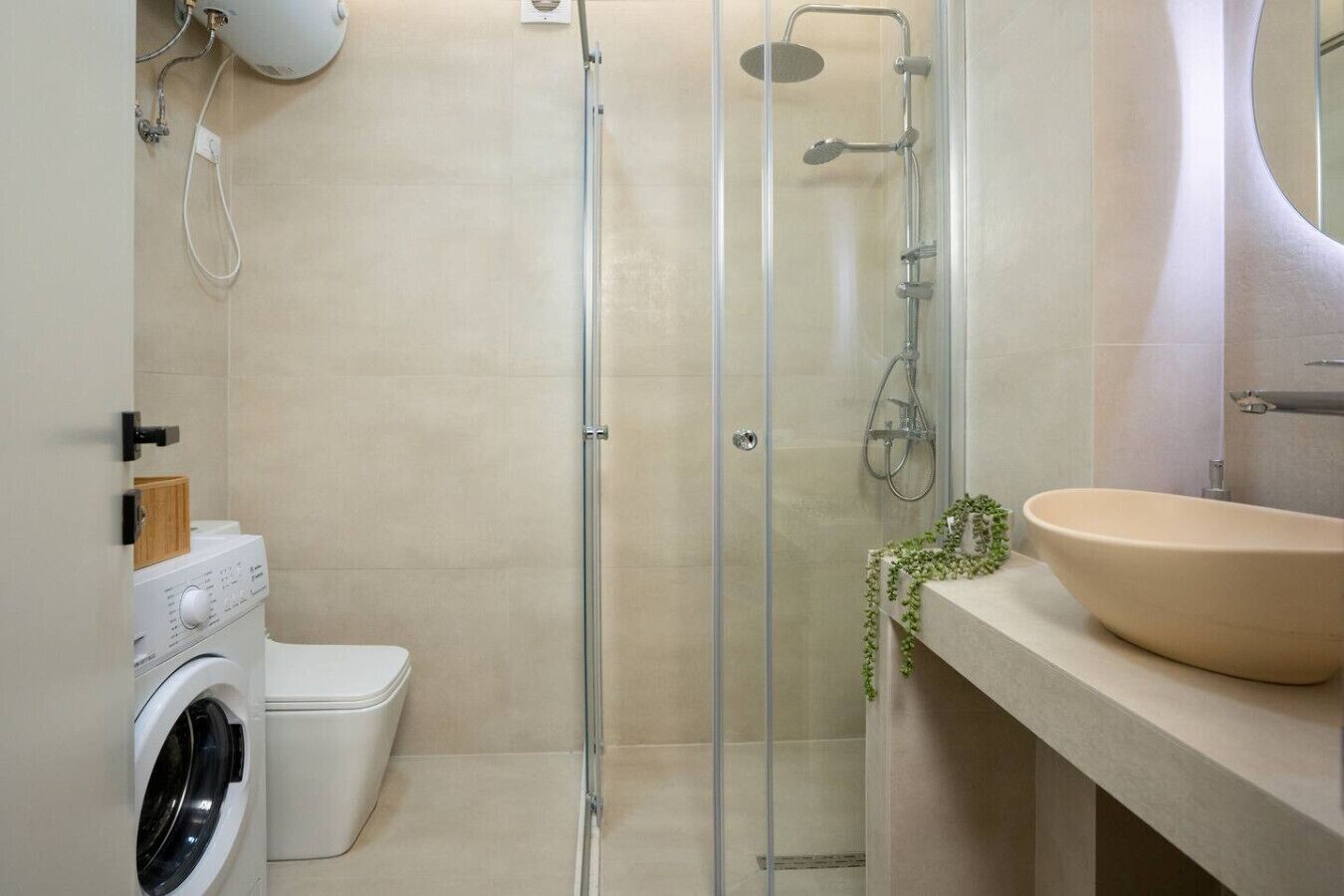 Un baño moderno con ducha acristalada, lavadora y un lavabo espacioso.