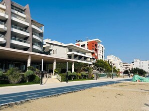 A multi-story hotel with balconies, a covered walkway, and a sandy beach area. - Sea view-Sunny Apartment by TOK (Durrës)