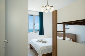A bedroom with a bed, a view of the sea through a window, and a chandelier. - Sea view-Sunny Apartment by TOK (Durrës)