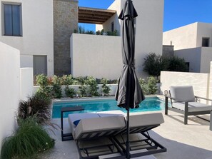 Ein Poolbereich mit Liegestühlen, einem Sonnenschirm und einem Pool.