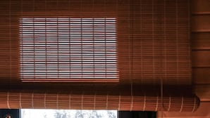 Una ventana con vista a árboles, una pared de madera y una persiana.