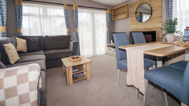 A cozy living area with a sofa, chairs, a small table, and a TV. - Coastal Escape (Par)