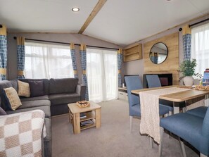 A cozy living area with a sofa, chairs, a small table, and a TV. - Coastal Escape (Par)