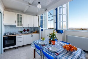 A kitchen with white cabinets, a blue and white checkered tablecloth, and a view of the sea through large windows. - GuestHost - Charming 50 sqm apartment, located on the 1st floor of a modern building (with lift), for 4 people and equipped with a shared swimming pool (for a fee) and free private parking space.The property is located in Calambrone, with direct access t (Calambrone)