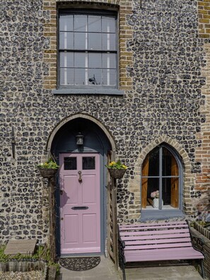A stone building with a pink door and a window with a grid pattern. - 17th-Century Flint Cottage by Viking Bay (Kent)