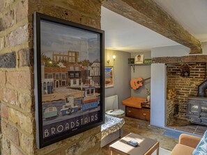 Un salon chaleureux avec une carte encadrée, une guitare, une cheminée et un coin salon confortable.