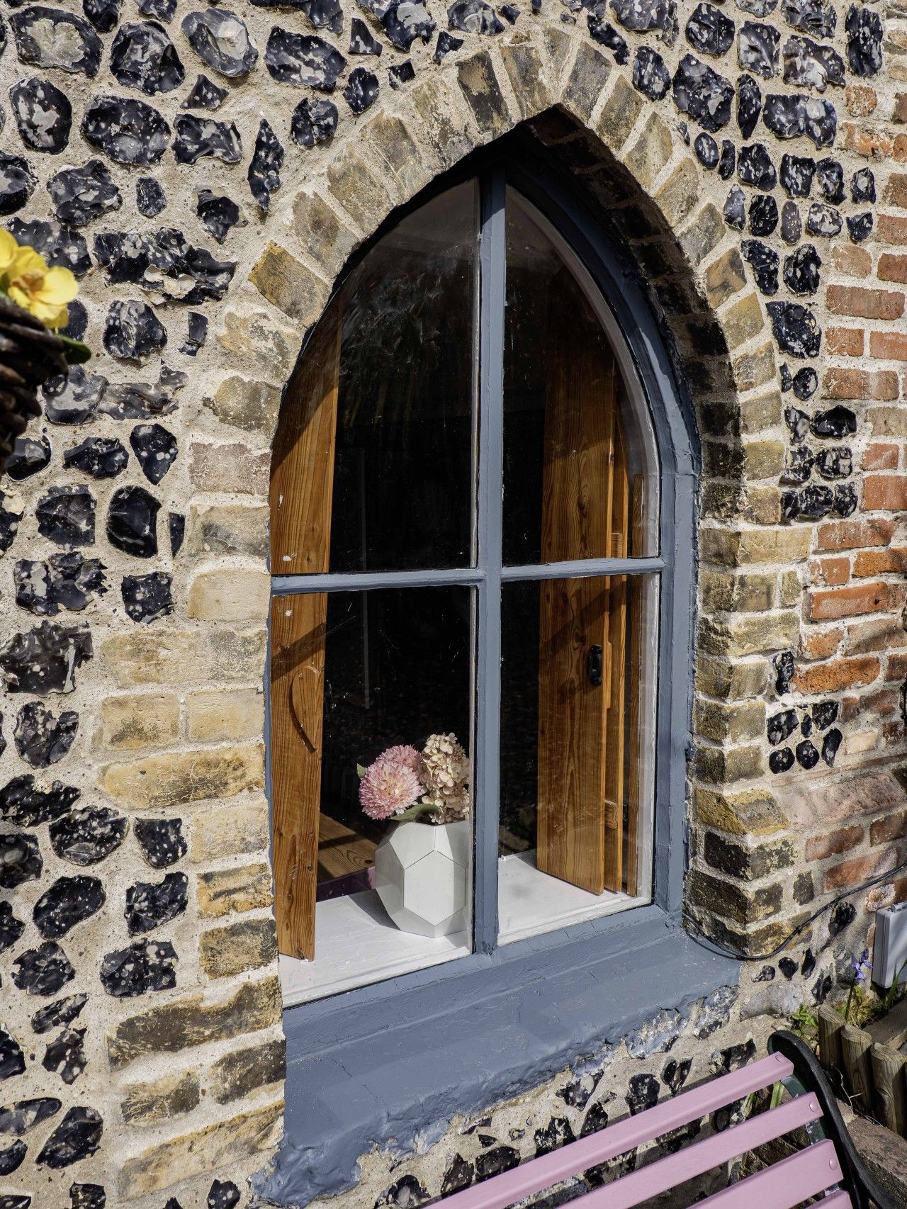 A stone building with a large arched window and a wooden door.