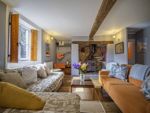 Un salon chaleureux avec une cheminée, des canapés et une guitare.