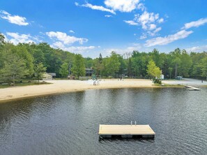 Ein Park am Seeufer mit Sandstrand, Picknicktischen, einem Spielplatz und einer Anlegestelle.