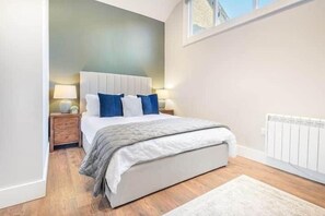 Une chambre à coucher avec un lit, des tables de chevet, un radiateur et une fenêtre.