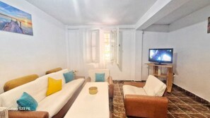 A living room with a sofa set, a coffee table, a television, and a painting on the wall. - Casa Cu Obloane Rosii By Cochilia (Eforie Nord)