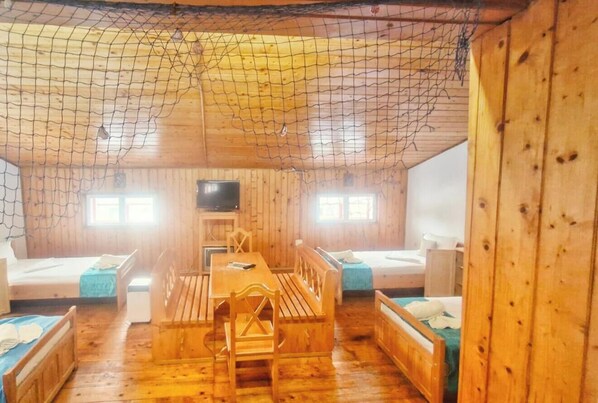 A wooden cabin with a dining table, benches, and two beds. - Casa Cu Obloane Rosii By Cochilia (Eforie Nord)