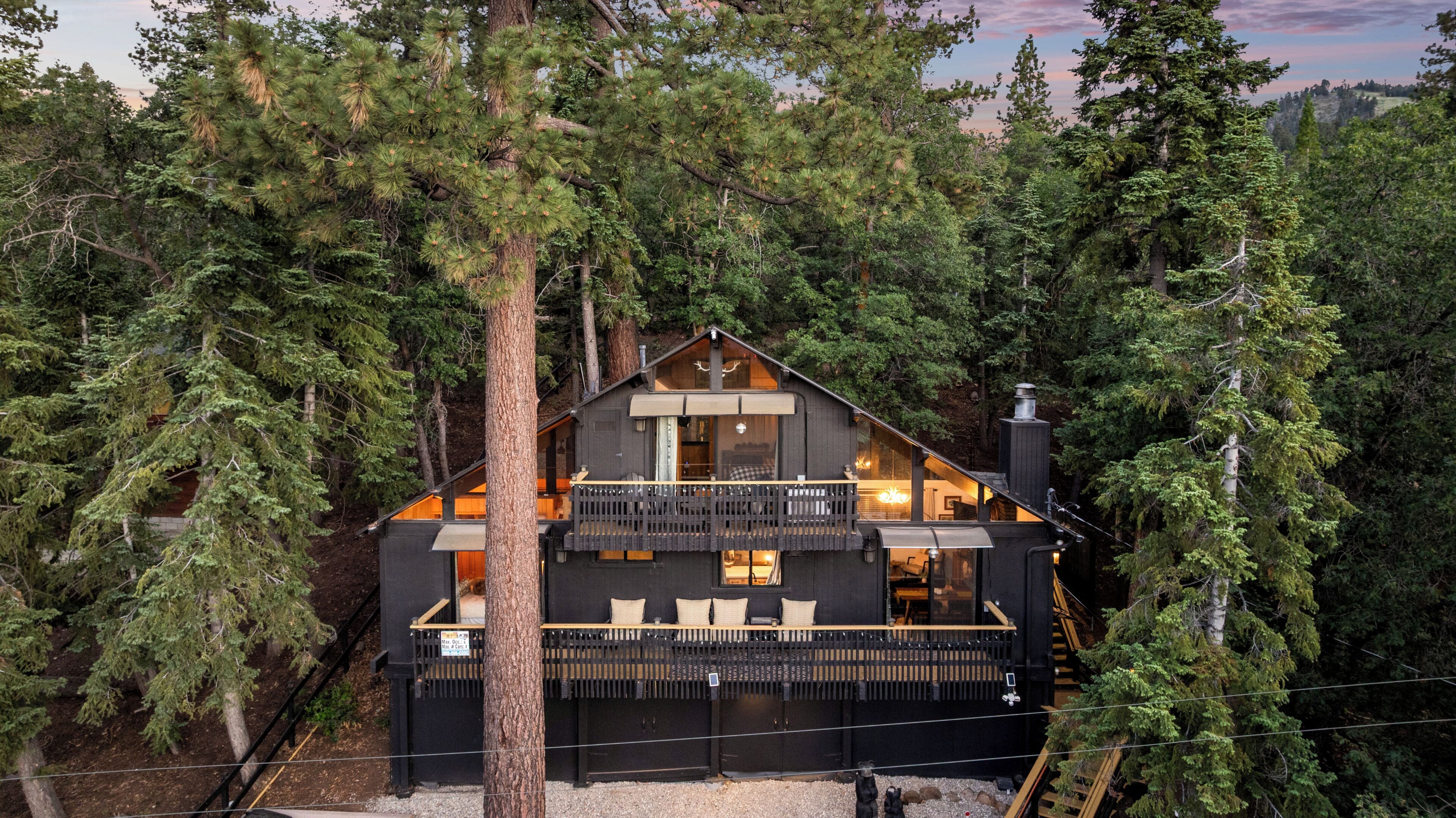 A cabin with a balcony, surrounded by dense forest.