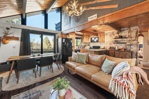 Een moderne keuken met houten kasten, een eethoek met tafel en stoelen, en een woonkamer met een bank en een open haard.