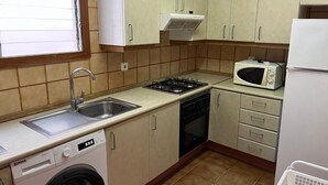 A compact kitchen with a washing machine, a microwave, and a stove. - Spacious 4 bedroom apartment in first line of sea. Rodes Lux-61 (Calafell)