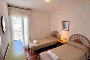 A room with two single beds, a small table, a lamp, and a framed picture on the wall. - Spacious 4 bedroom apartment in first line of sea. Rodes Lux-61 (Calafell)