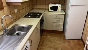 A compact kitchen with a sink, stove, microwave, and refrigerator. - Spacious 4 bedroom apartment in first line of sea. Rodes Lux-61 (Calafell)
