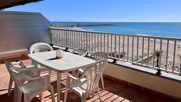 A balcony with a table and chairs, overlooking a beach and the sea. - Spacious 4 bedroom apartment in first line of sea. Rodes Lux-61 (Calafell)