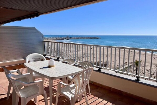 A balcony with a table and chairs, overlooking a beach and the sea. - Spacious 4 bedroom apartment in first line of sea. Rodes Lux-61 (Calafell)