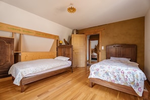 Un dormitorio con dos camas de madera, un armario y una puerta que da a otra habitación.
